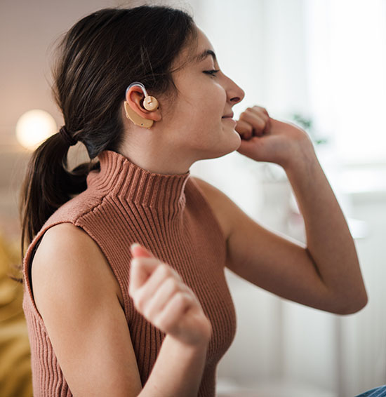 Teenage girl with hearing aid listening music in her room.