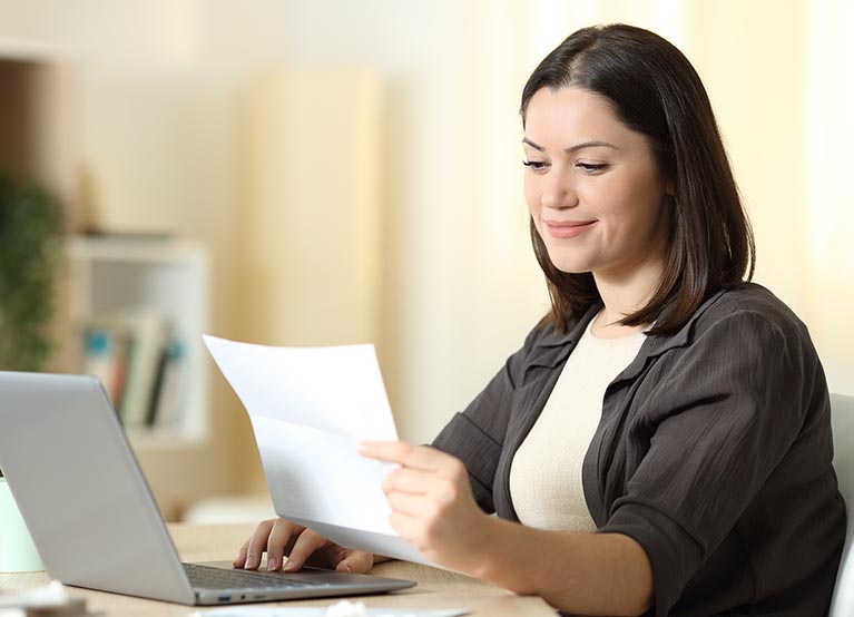 Woman reading a letter using laptop at home