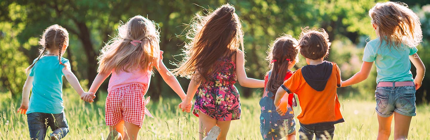 Large group of kids, friends boys and girls running in the park on sunny summer day in casual clothes .