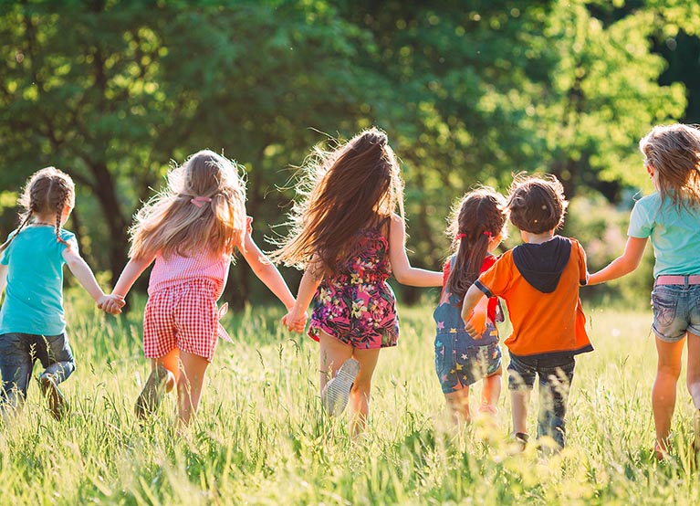Large group of kids, friends boys and girls running in the park on sunny summer day in casual clothes .
