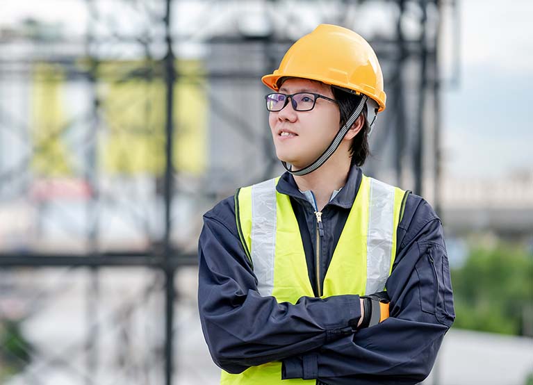 Asian maintenance worker man wearing reflective suit and safety helmet working at construction site. Civil engineering, Architecture builder and building service concepts