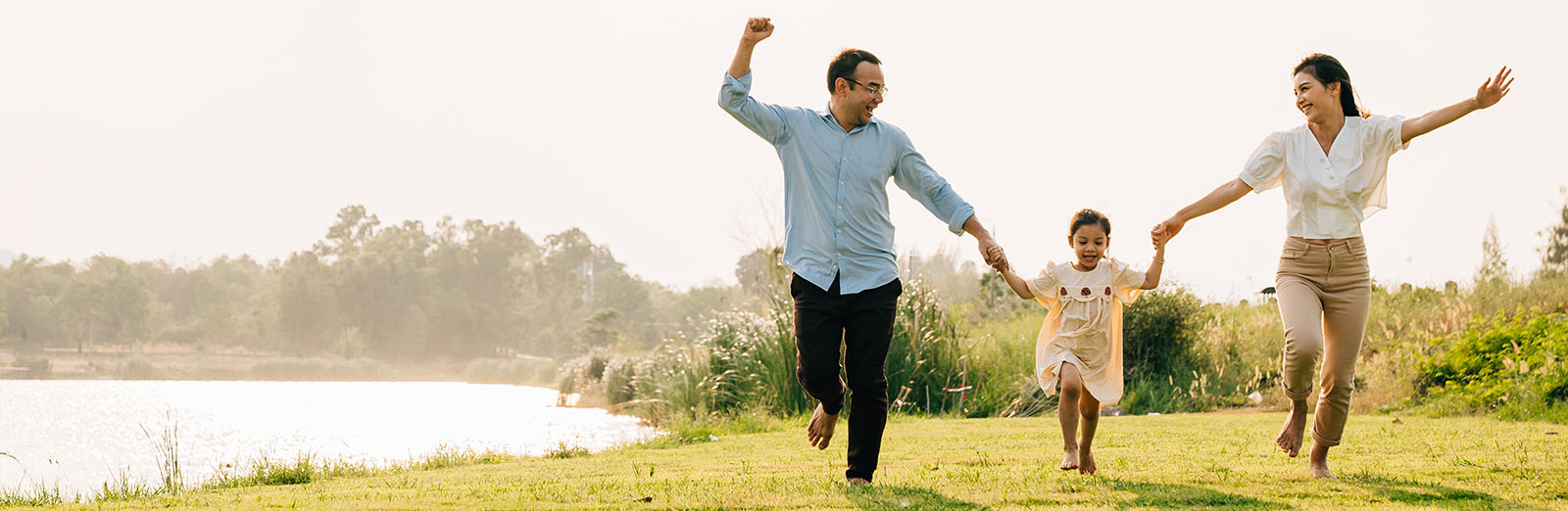 Asian family running and playing together in a beautiful nature setting, with a sunny sky and green grass all around, feeling carefree and happy, Happy Family Day Concept