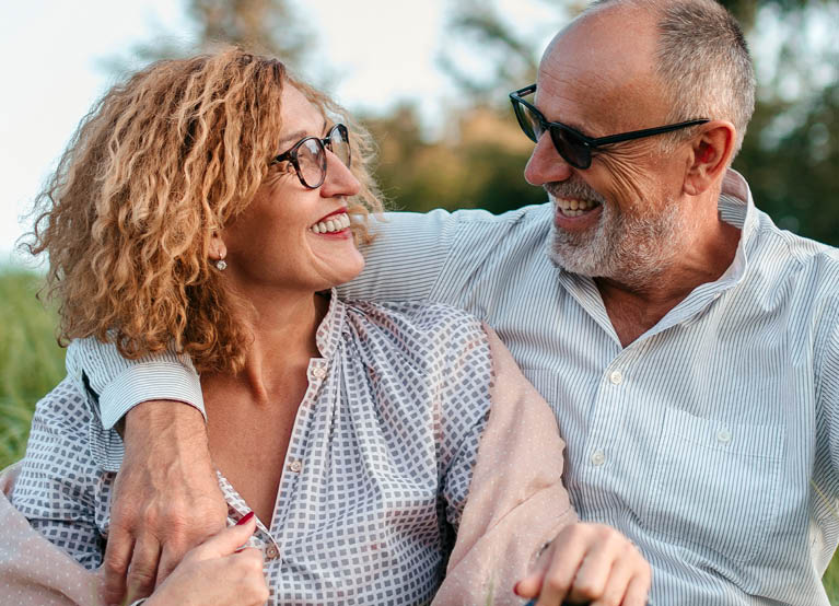 middle age man and woman with glasses  smiling at each other outdoors 767x554.jpg
