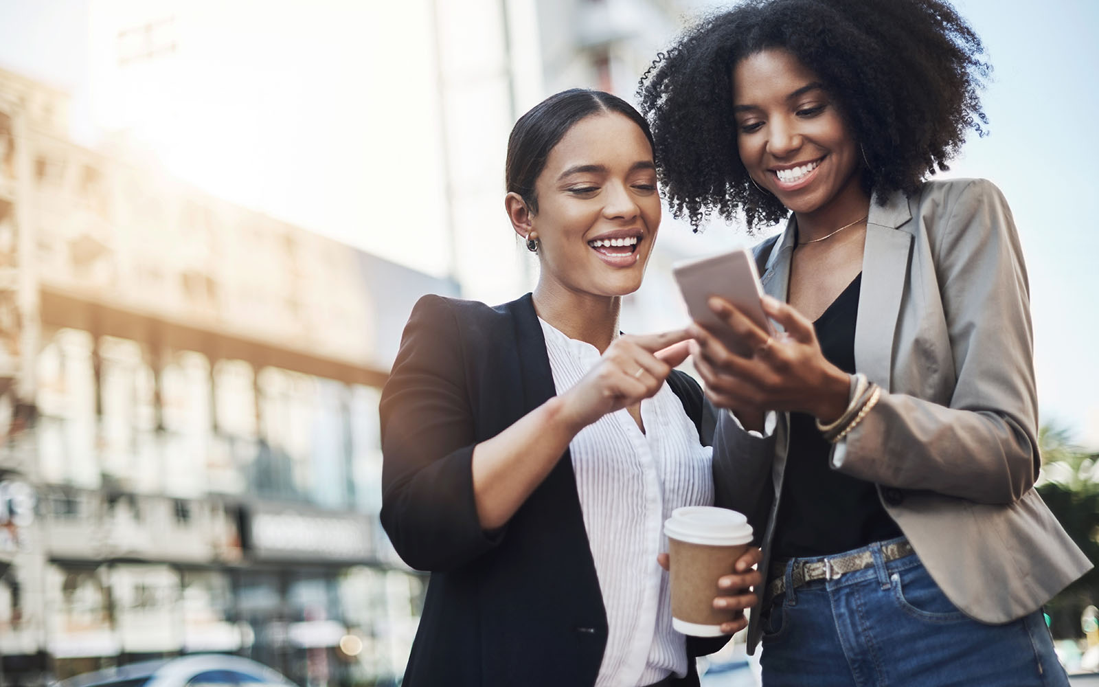 Reaching out to new networks. Shot of two businesswomen looking at something on a cellphone in the city.