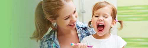 mother helping daughter brush teeth-mobile.jpg